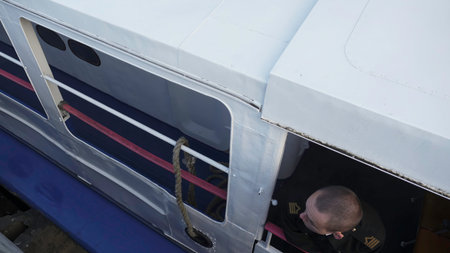 Sailor throwing rope from boat window to dock worker. Clipの写真素材