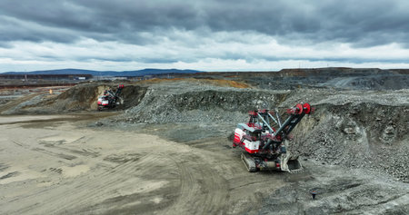 Excavator loading rocks in mining area under cloudy sky. Stock clip