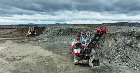 Excavator mining ore in open pit mine under cloudy sky. Stock clip