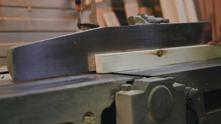 Feeding Wood Through Spinning Blade, Precise Woodworking Under Warm Workshop Lighting Conditions ....