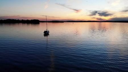 Sailboat anchored on a calm lake at sunset