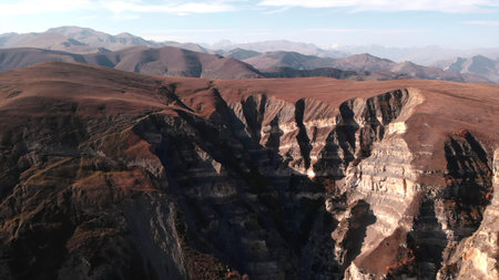 cliffs shadowed deep, geologist examines erosion patterns and rock structures within steep canyon...