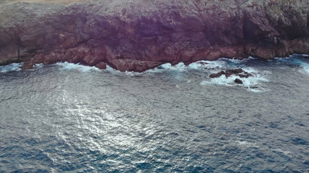 Aerial view flying over sea and rocky cliffs revealing lighthouse.の写真素材