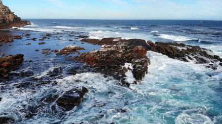 Violent Waves Crash Against Cliffs, Wild Surf Pounds Rugged Coast Beneath Lookout Tower.の写真素材