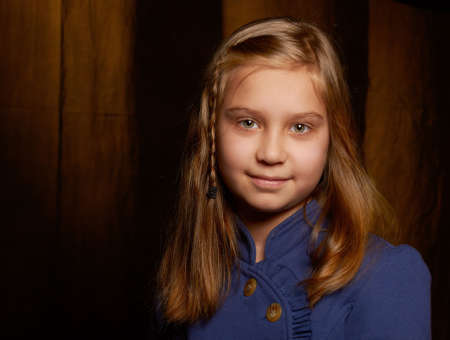 Portrait of a smiling girl with long blonde hair in a blue dressの写真素材
