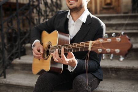 Man playing guitar , close up. Young hipster siting on the stairs.の写真素材