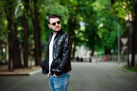 Image of serious handsome man wearing black leather jacket, white tshirt and sunglasses.の写真素材