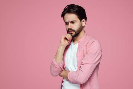 Photo of thoughtful young man isolated over pink background wall.の写真素材