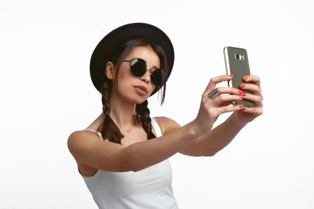 Cool girl shooting selfie on front camera isolated on white background