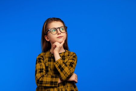 Smart girl in nerdy glasses touching cheek and looking up while thinking