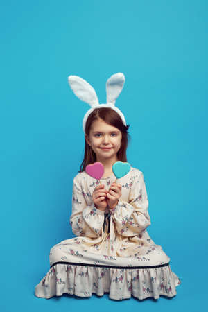 Nice cute kid girl having two cookies in heart shape on sticksの写真素材