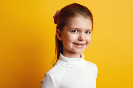 Pretty little girl in white turtleneck posing adorably on yellow background