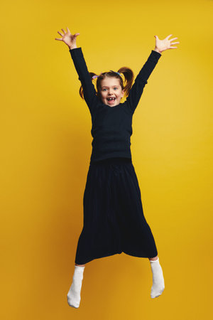 Full body of young cute girl smiling and raising hands up while jumping
