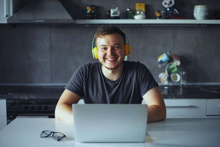 Happy relaxed caucasian man wear wireless headphones, smiling while looking at camera, finished work listening music, feel peace of mind, home officeの写真素材