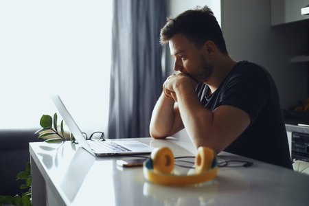 Concerned serious man lost in thoughts in front of laptop, focused male thinking of problem...