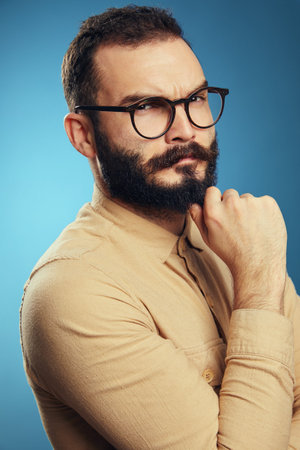 Close up portrait of serious thoughtful adult bearded businessman in casual beige shirt and...