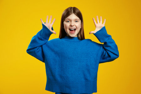 Surprised youngster wearing bright blue sweater energetically displaying open hands, radiating happiness and excitement.の写真素材