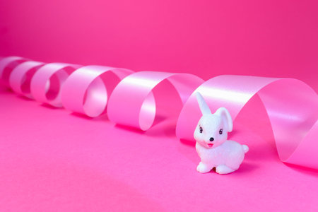 Little white rabbit and pink ribbon background