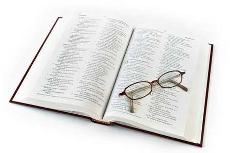 Open bible with folded reading glasses. Focus on glasses.