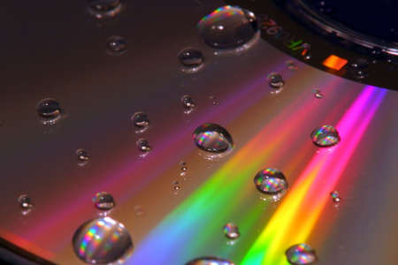 A colorful cd-rom with scattered water droplets on its surface.の写真素材