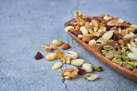 Mix dried fruits with nuts, pistachios, cashew nuts in wooden bowl on gray concrete background.の写真素材