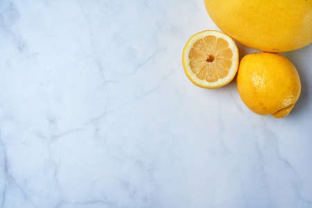 Top view of fresh lemons on kitchen marble. Grapefruit, open lemon and whole lemon, antioxidant vitamin on white background.の写真素材