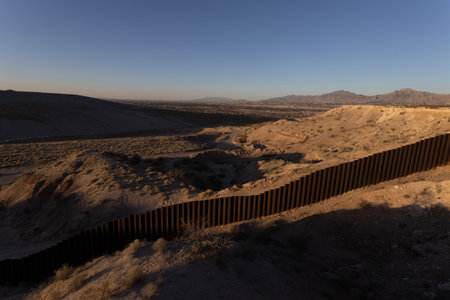 View of a desert landscape with a prominent border fence, showcasing the arid environment and...