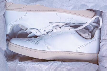 New casual white sneakers in a shoe box, concept picture, online shopping, background theme, new shoes covered in wrapping paperの写真素材