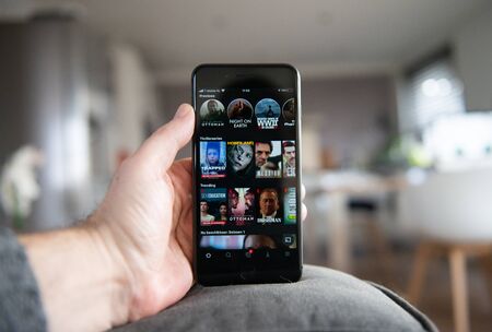 Amsterdam, The Netherlands, 02/06/2020, Man holding iphone 8 plus, Netflix start screen on mobile phone. Netflix online video, content streaming subscription service.のeditorial素材