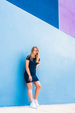 Happy beautiful young woman posing by a colorful wallの写真素材