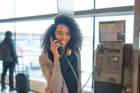 happy Woman at the airport talking by public phoneの写真素材