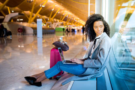 woman working with laptop at the airport waiting at the windowの写真素材
