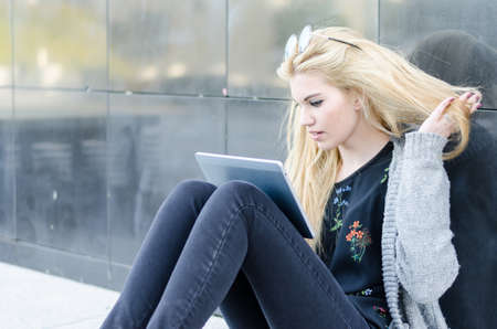 happy blonde student woman sit on the floor with a tabletの写真素材