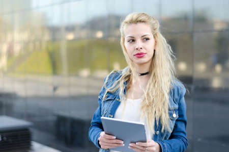 happy blonde student woman with tablet in a reflection wallの写真素材