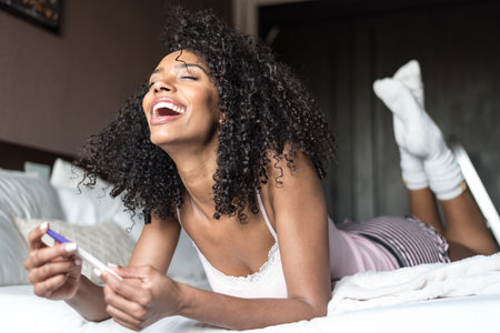 happy woman on bed with a pregnancy test