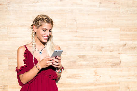 Beautiful blonde woman smiling and using mobile phone outdoor portrait close upの写真素材