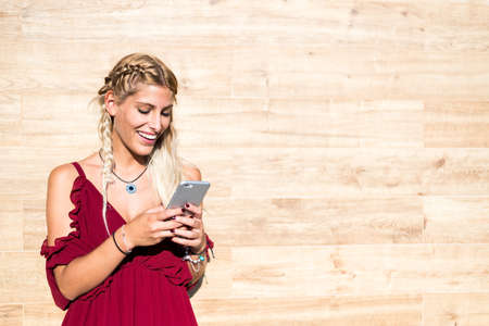 Beautiful blonde woman smiling and using mobile phone outdoor portrait close upの写真素材