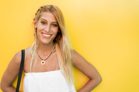 Happy blonde woman in a yellow background wall isolatedの写真素材