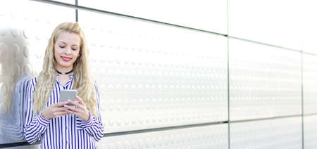 happy blonde young woman outdoor using her mobile phone isolatedの写真素材