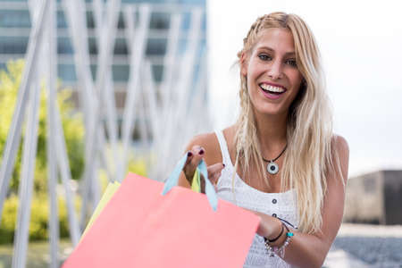 Blonde happy young woman shopping with bags outdoors.の写真素材