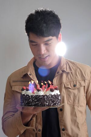 Asian man with birthday ice-cream cake on fireの写真素材