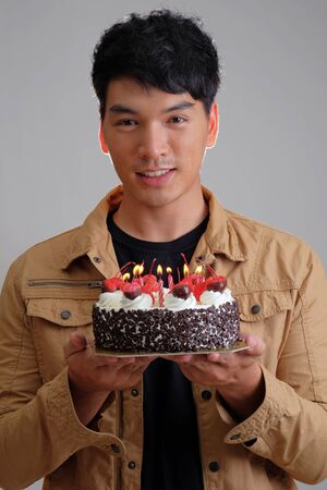 Asian man with birthday ice-cream cake on fireの写真素材