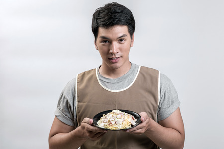 Asian man in apron with spaghetti carbonaraの写真素材