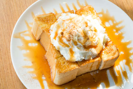 Golden honey toast in the white dish with whipped cream on topの写真素材