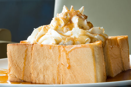 Golden honey toast in the white dish with whipped cream on topの写真素材