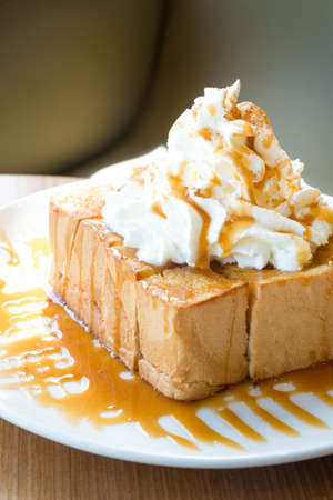 Golden honey toast in the white dish with whipped cream on topの写真素材