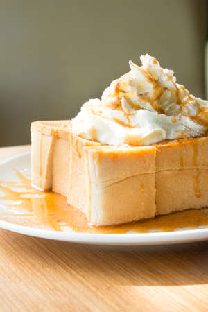 Golden honey toast in the white dish with whipped cream on topの写真素材