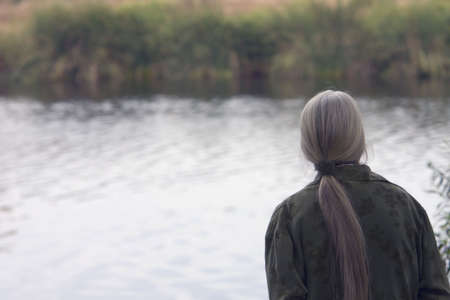A senior woman  is enjoying a lake's beauty.の写真素材