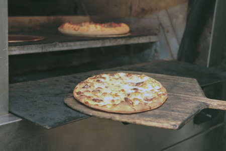 A pizza is being taken out of the pizza oven.の写真素材