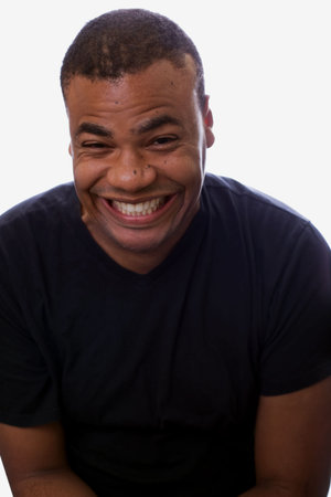 A young man is giggling while sitting in front of a white background.の写真素材